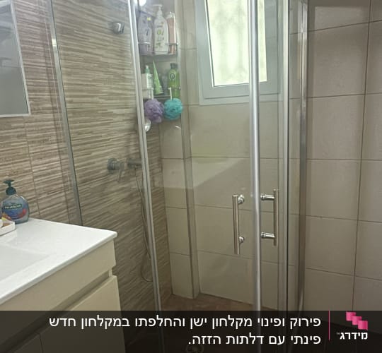 מקלחון זכוכית עם מוצרי טיפוח ומגבות רחצה
